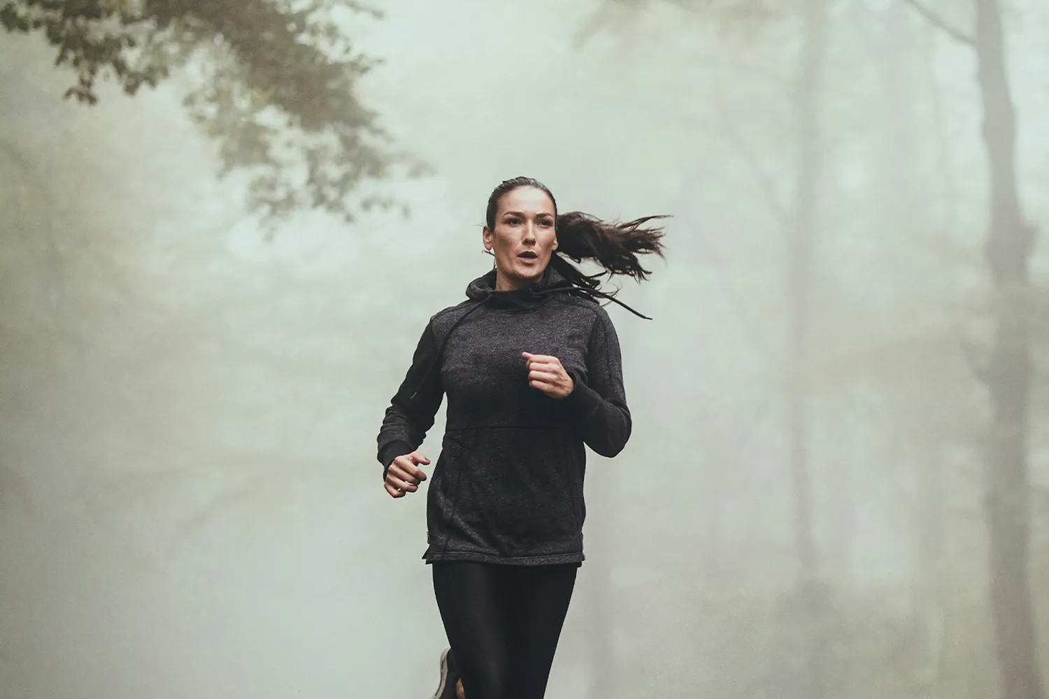 A person running outdoors on a wooded road, representing a return to normal energy and activity