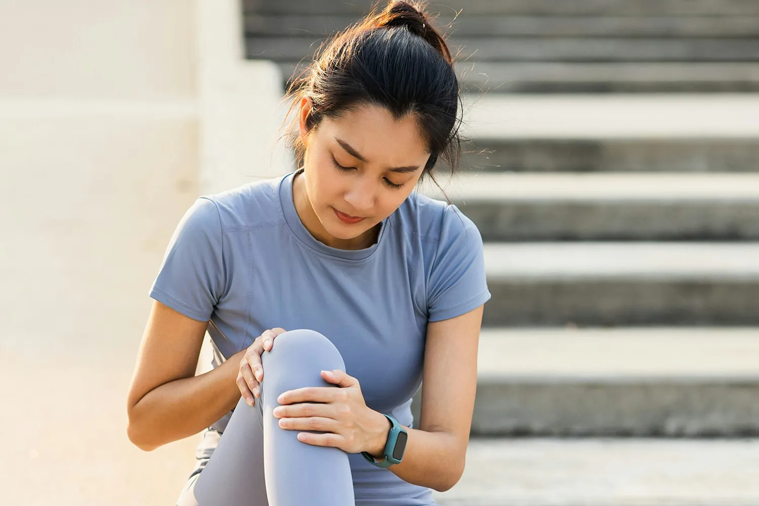 A person seated on steps holding their knee, the kind of everyday pain regenerative therapy is used to treat